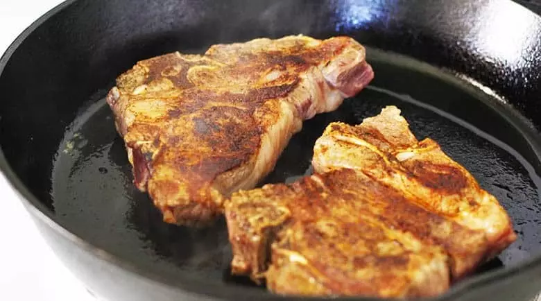 Two lamb chops in a skillet fried.
