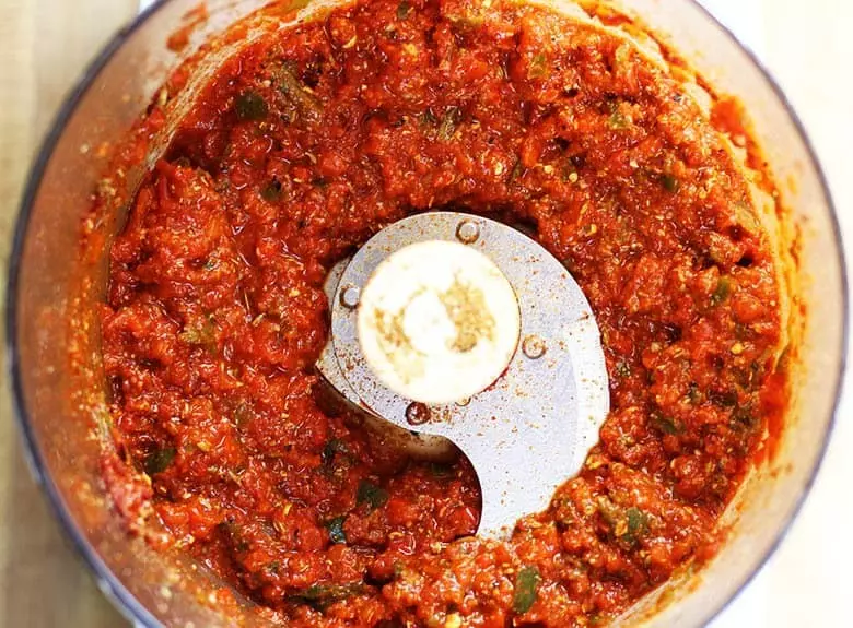 A food processor with harissa blended into a paste.