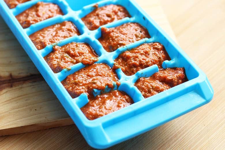 An ice cube tray with harissa paste in it.