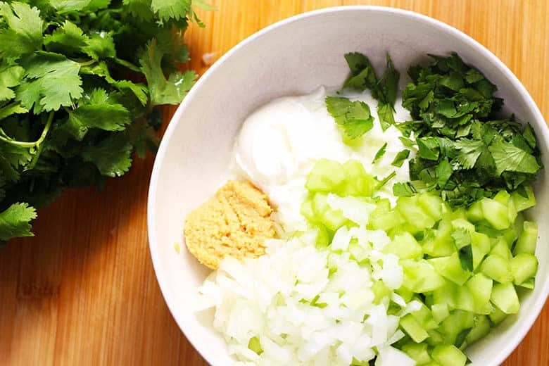 A bowl with yogurt, cucumber, garlic, cilantro and onion