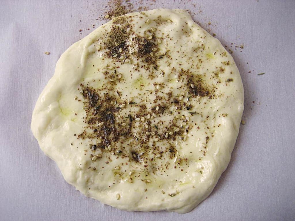 Spread dough with fingers and season with olive oil and Za'atar.