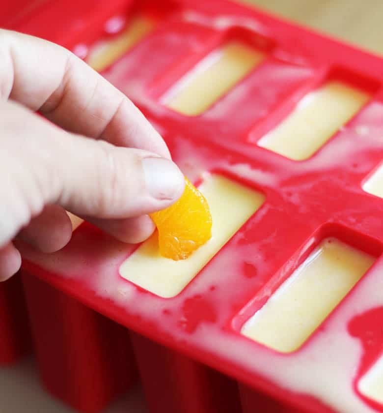 mandarin orange slices placed in a popsicle mould.