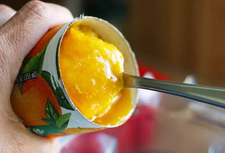 frozen orange juice concentrate being scooped out with a spoon.