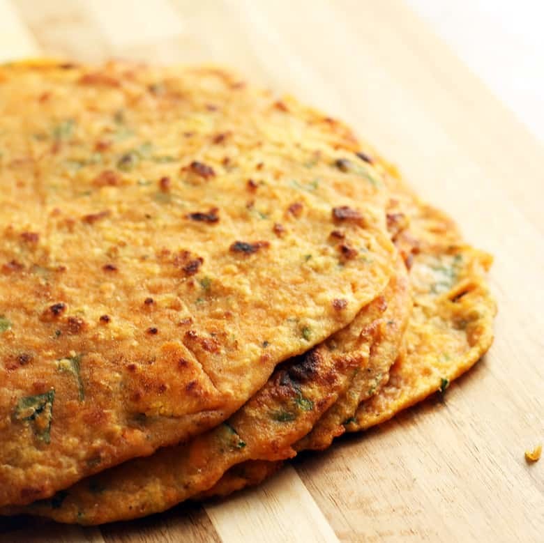 A pile of cooked parathas on a cutting board.