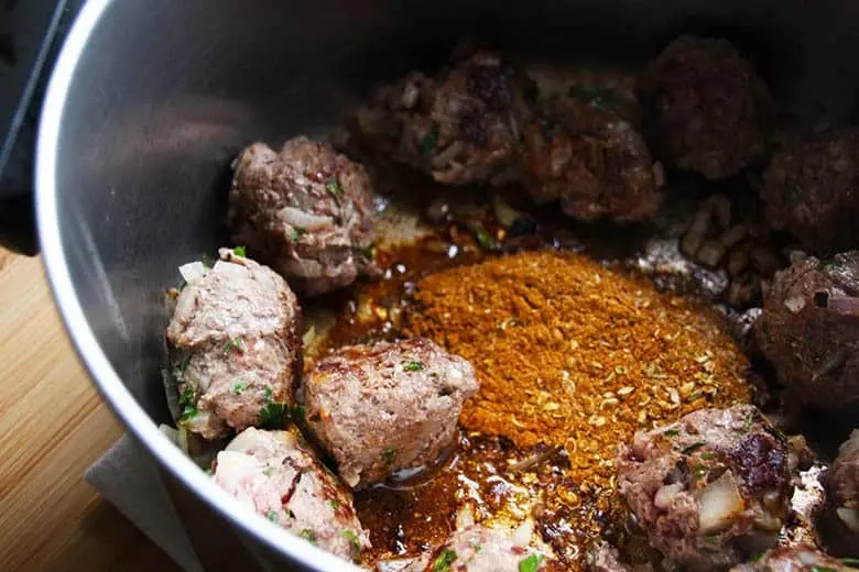 Elk meatballs sautéing in a pan with spices.