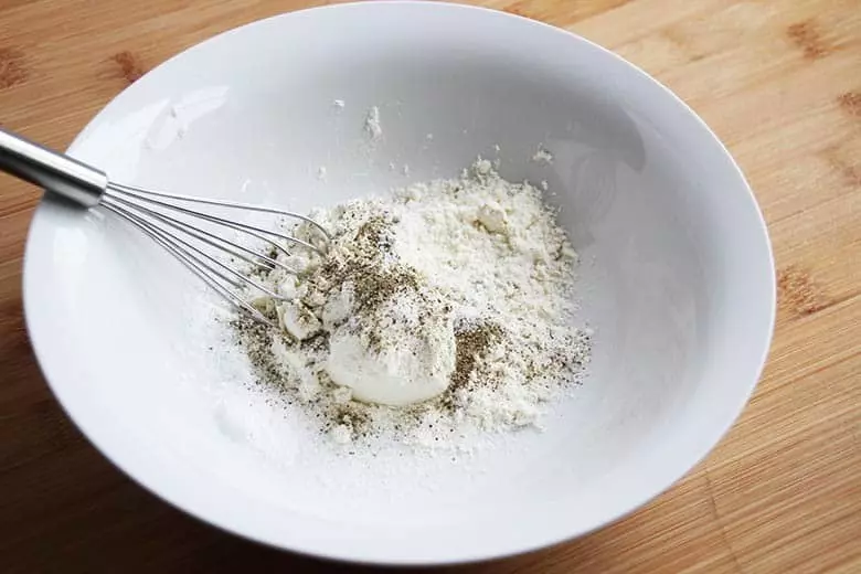 Flour, salt and pepper in a bowl with a whisk.
