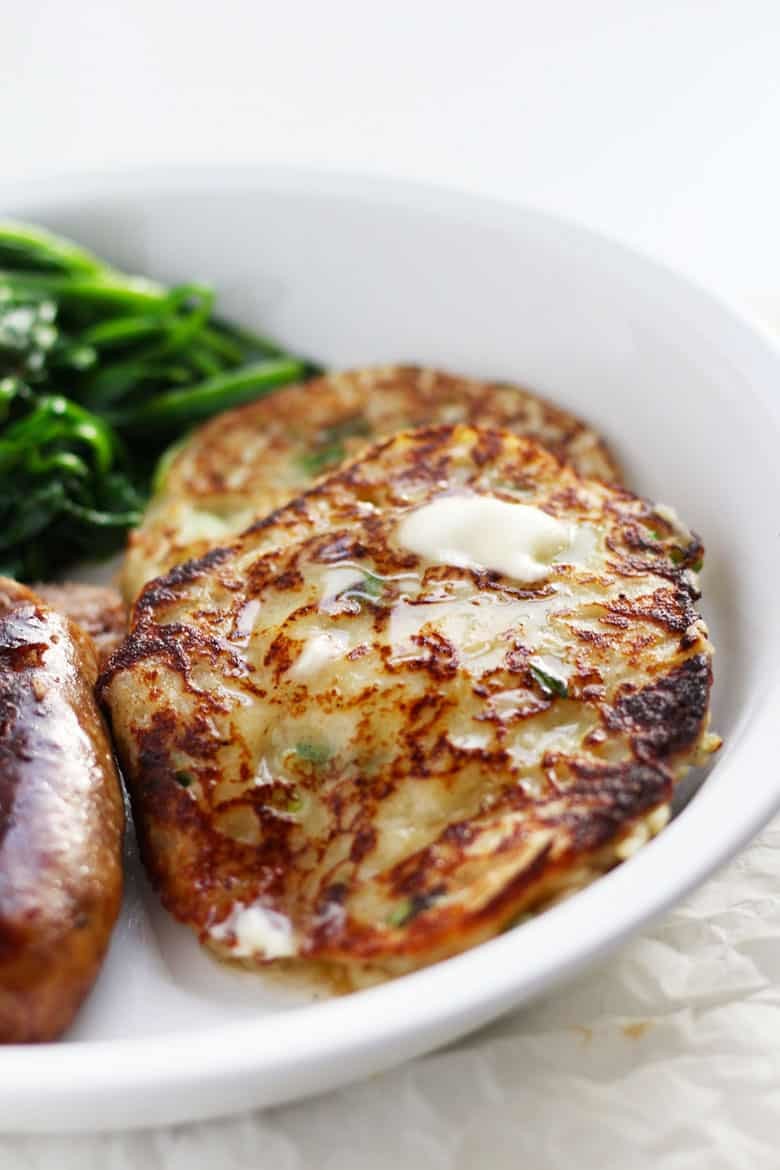 Boxty served with sausage and cooked greens.
