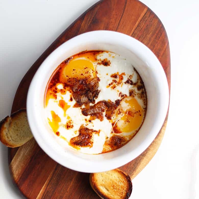 A bowl of Turkish Eggs with browned butter sauce in a white bowl.