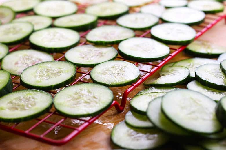 Sliced cucumber on a red cooling rack.