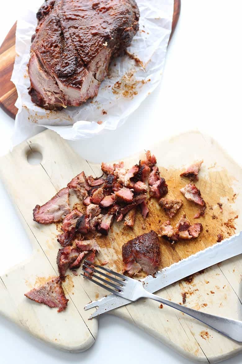 BBQ pork shredded with a fork on a cutting board.