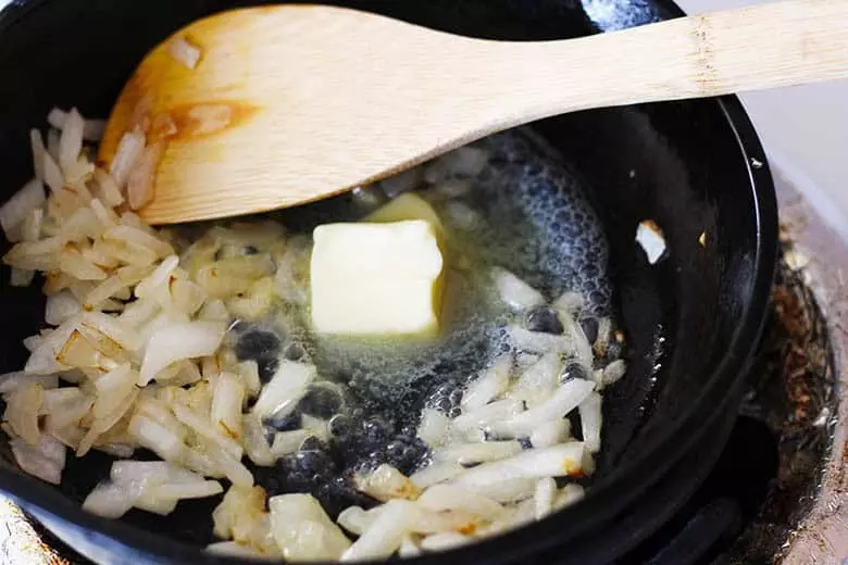 Butter and onions melting in a cast iron skillet.