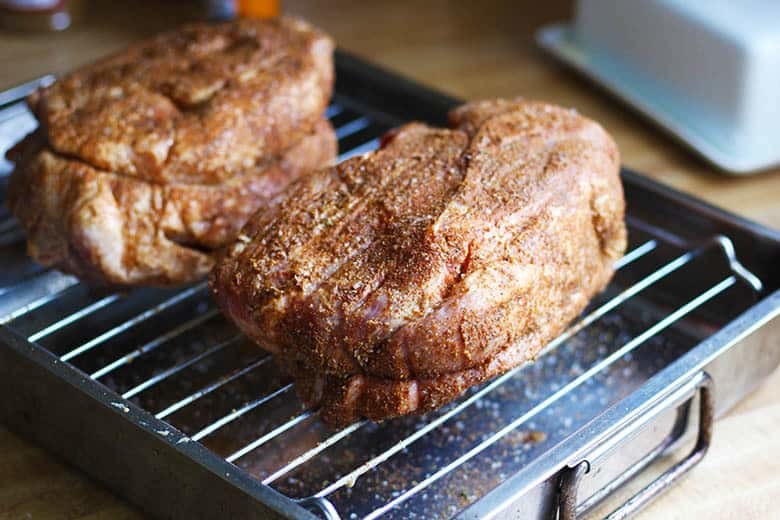 Two pork roasts resting on rack.