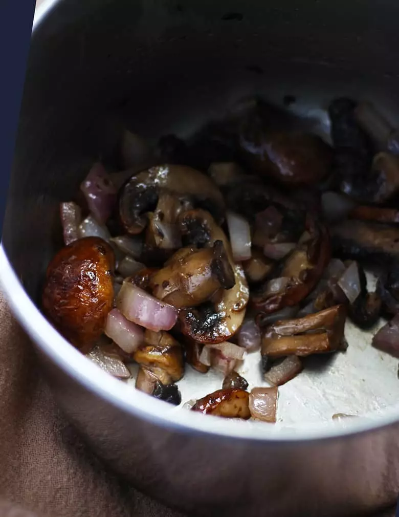 Mushrooms and onions cooked in a pan.