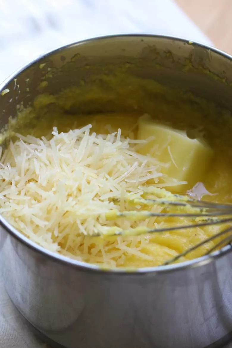 A pan with polenta and parmesan and melting cheese.