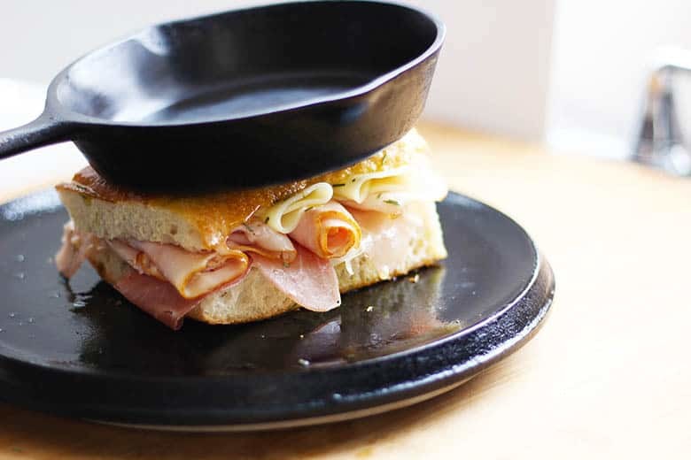 Panini sandwich being pressed using a second cast iron skillet.