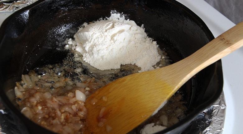 Flour in a cast iron skillet with shallots.