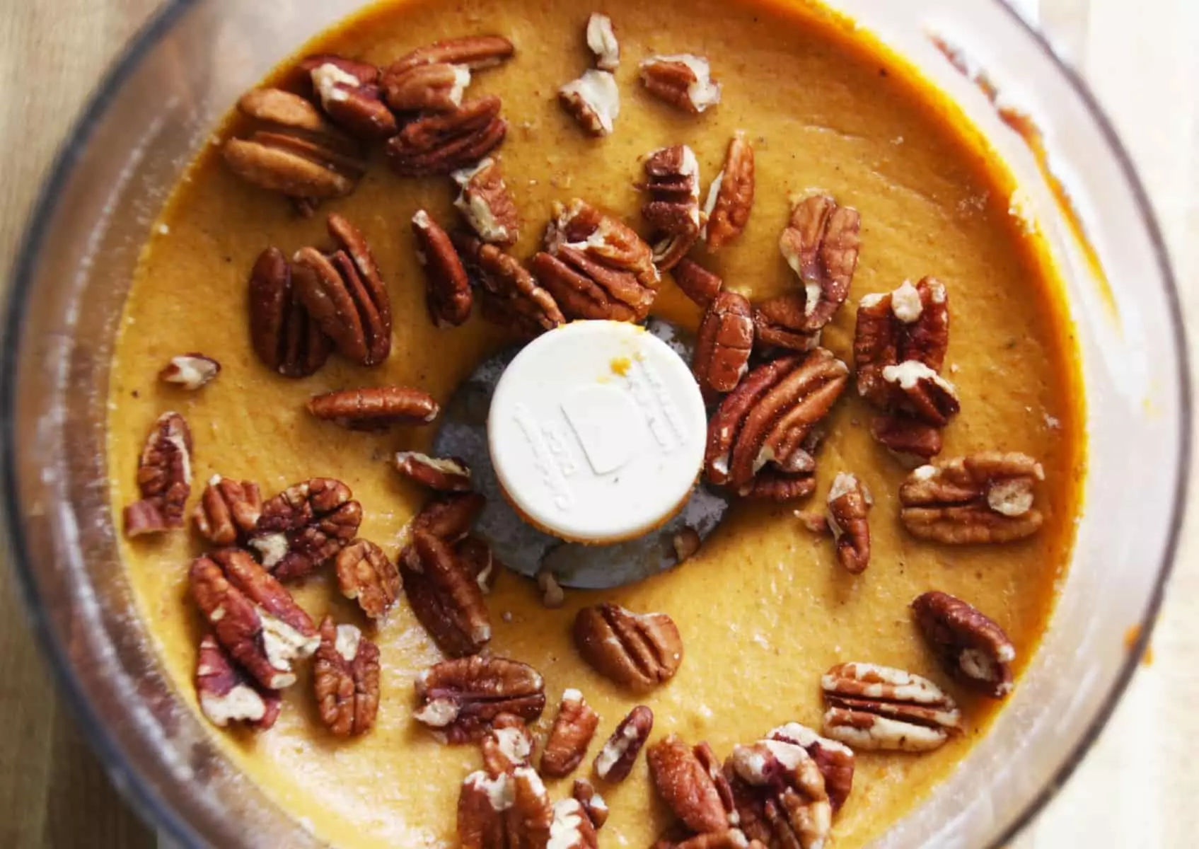 Food processor with batter and pecans.