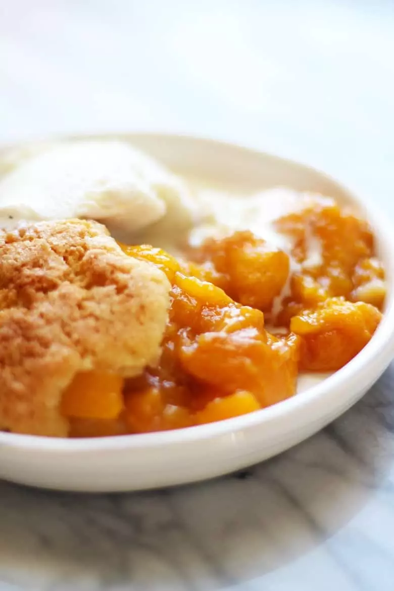 A bowl of French Peach Cobbler and ice cream.