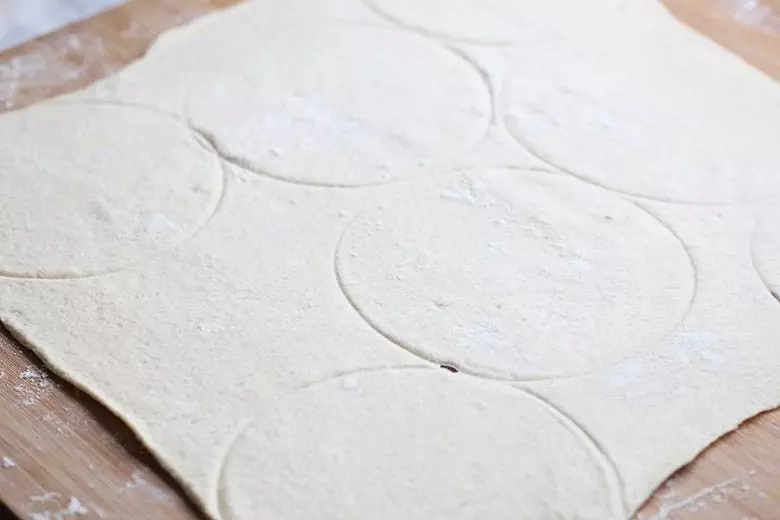 Pizza dough with circles imprinted.