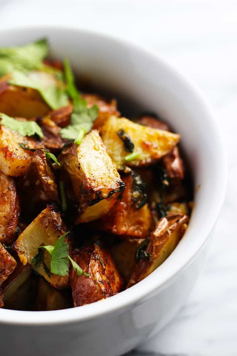 A bowl of cooked potatoes with herbs.
