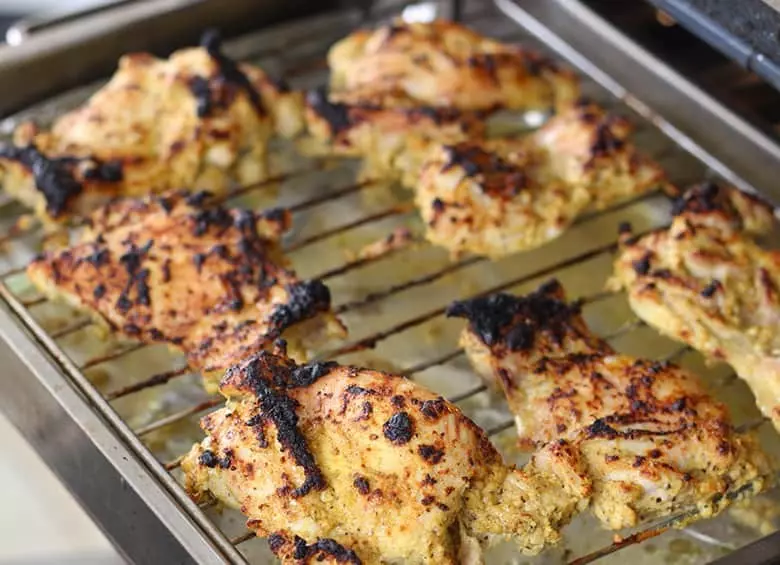Roasted and charred chicken on a rack.