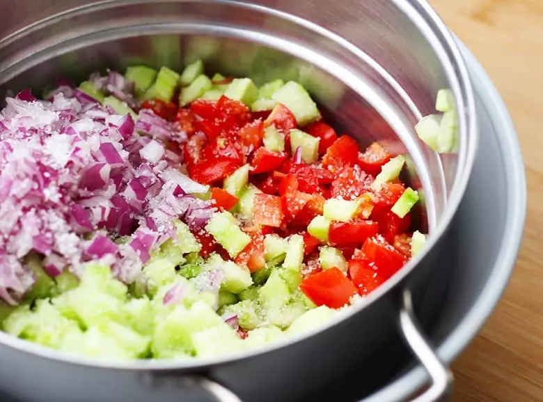 Chopped tomatoes, cucumbers, onions in a sieve.