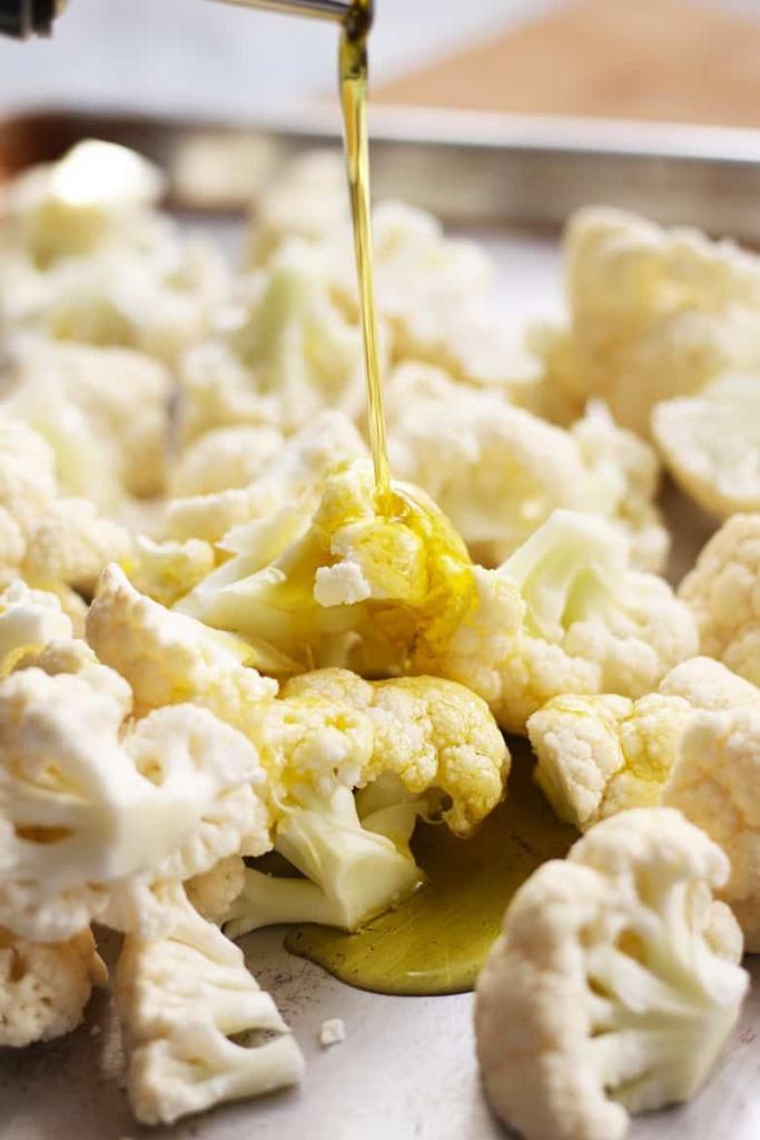 Drizzling olive oil on cauliflower.