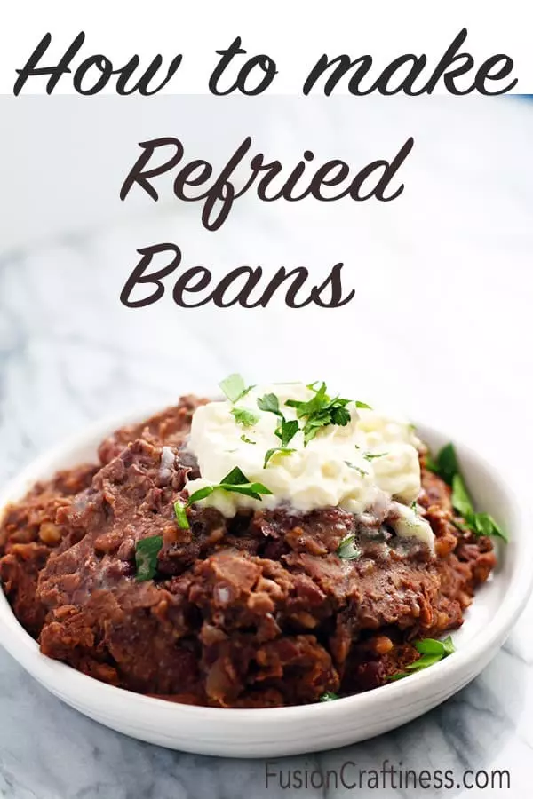 A bowl of refried beans with sour cream on top.