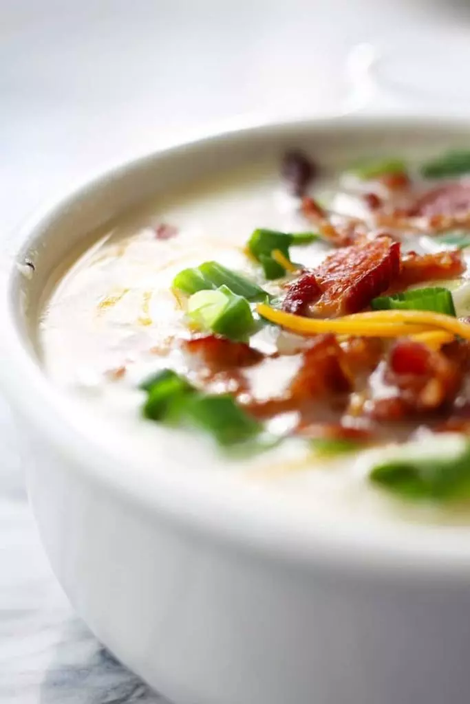 A bowl of potato soup with bacon and scallions.