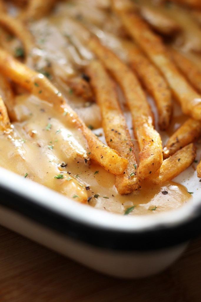 A white pan of fries with rarebit sauce.