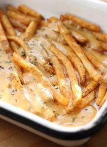 A white pan of fries with rarebit sauce.