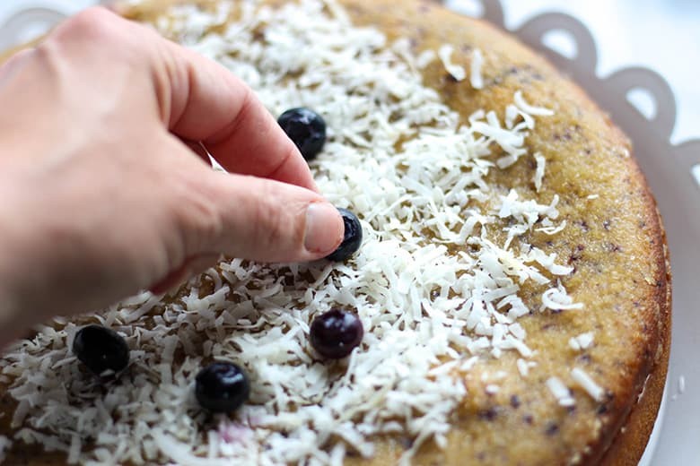 Garnishing cake with blueberries and coconut flakes.