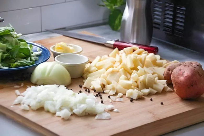 Potatoes, onion and cabbage on a cutting board.