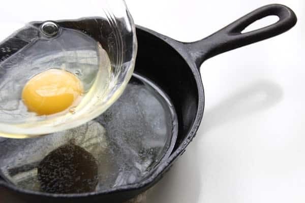 Pouring egg from bowl to skillet.