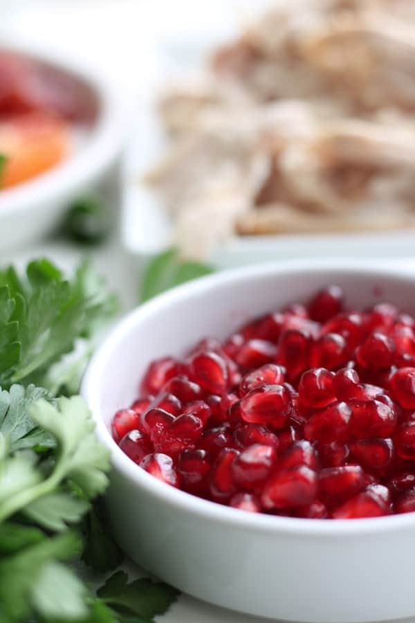 Pomegranate seeds in a white bowl.