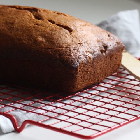 A golden loaf of banana bread on a cooling rack.