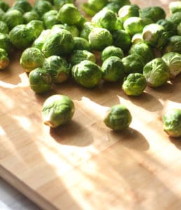A cutting board with Brussels sprouts.