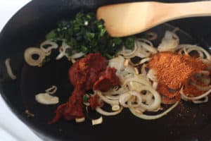 Onions, spices, tomato paste in a skillet.