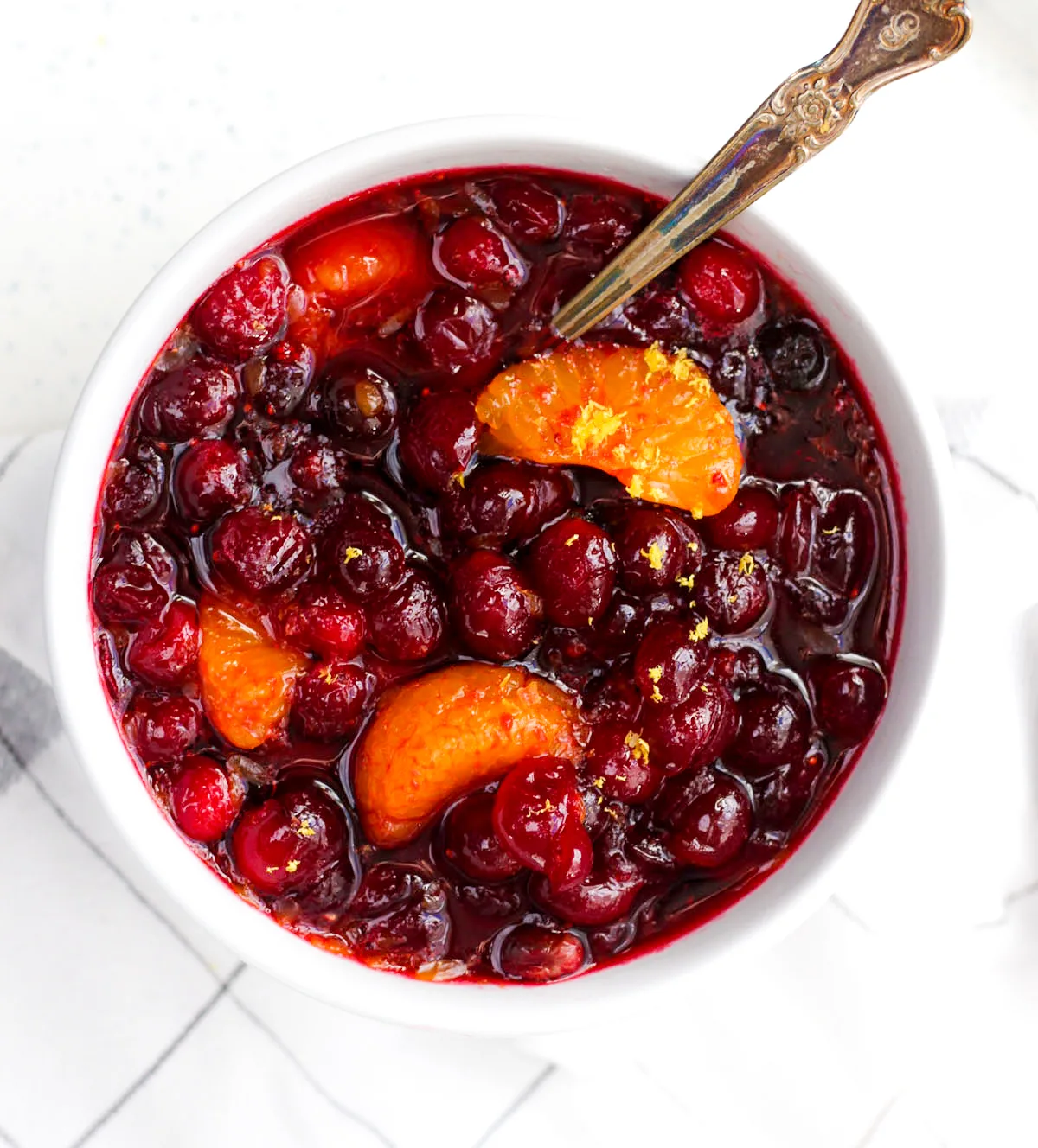 Homemade Orange Ginger Cranberry sauce in a white bowl with grated lemon rind.