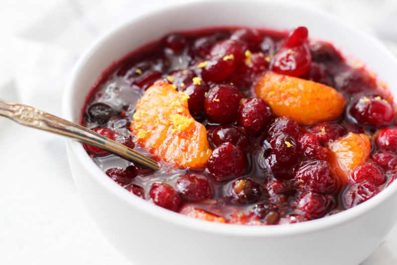 Homemade Orange Ginger Cranberry sauce in a white bowl with grated lemon rind.