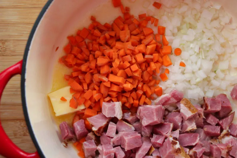 Carrots and onions in pot with ham.