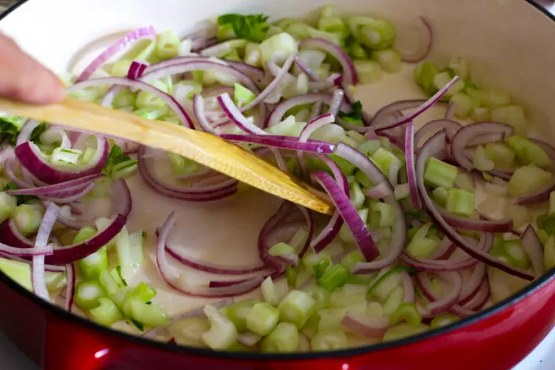 Chopped cabbage stems and red onions in pot.