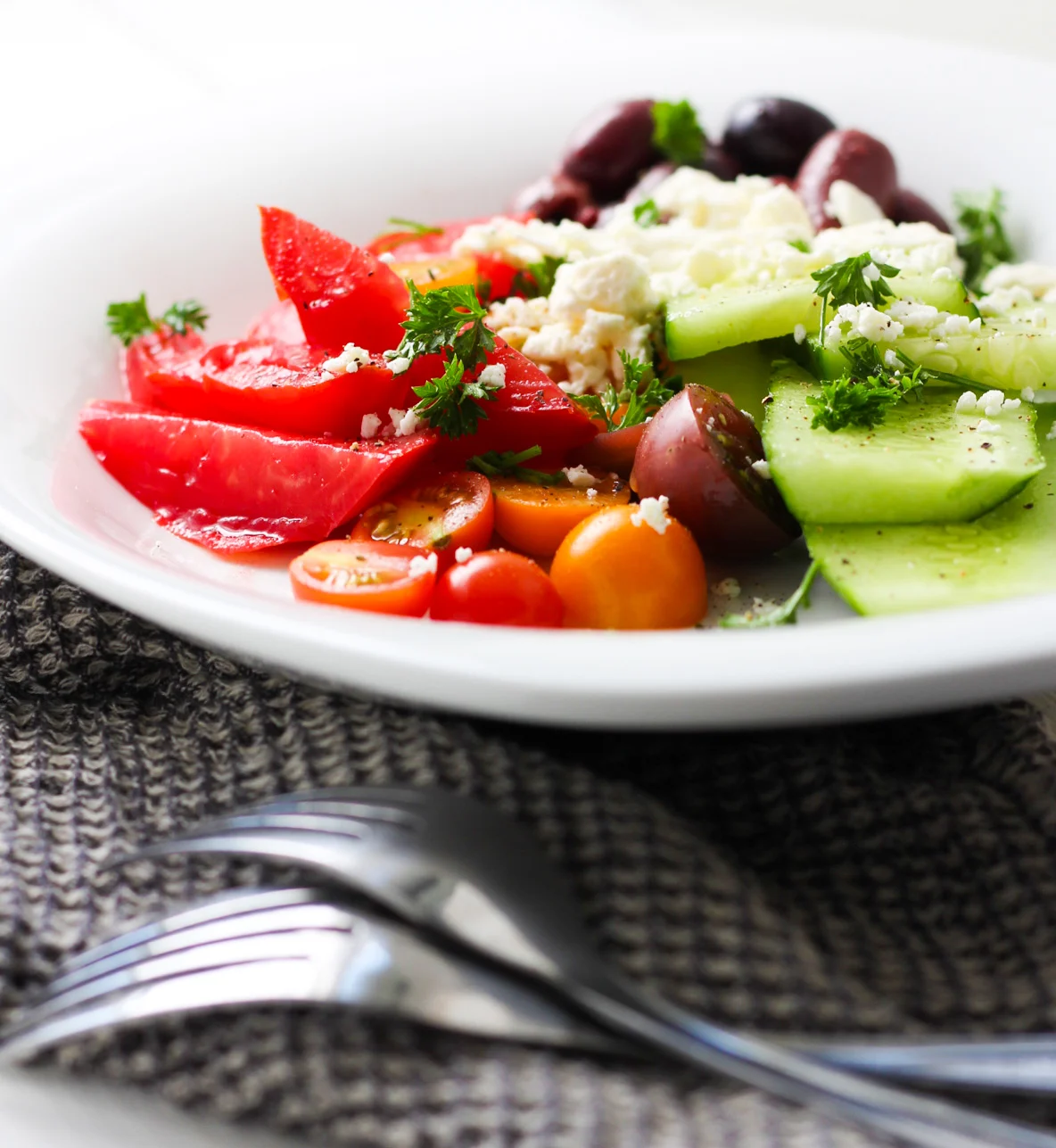 Greek salad with dressing on a white plate.
