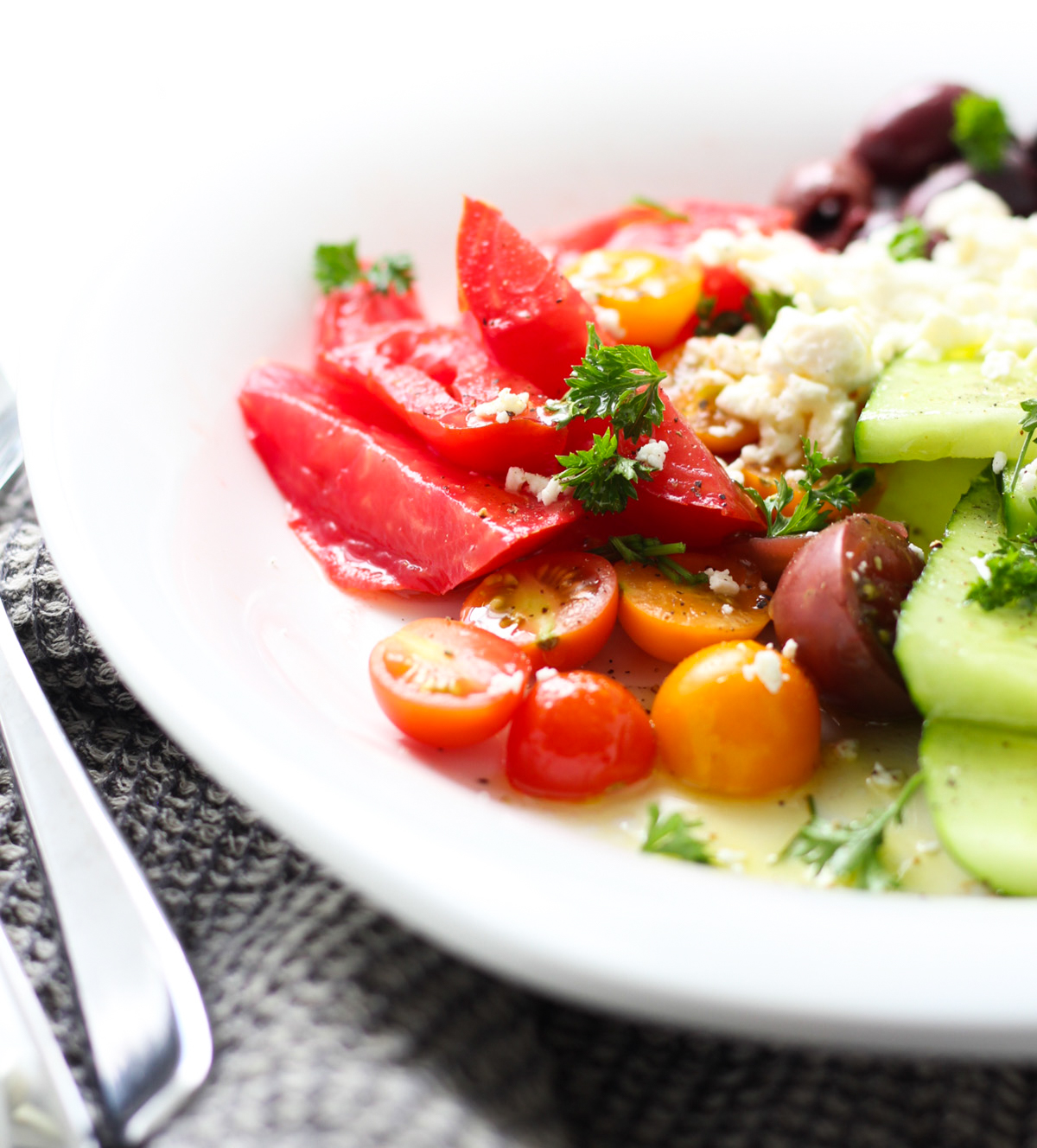Greek salad with dressing on a white plate.